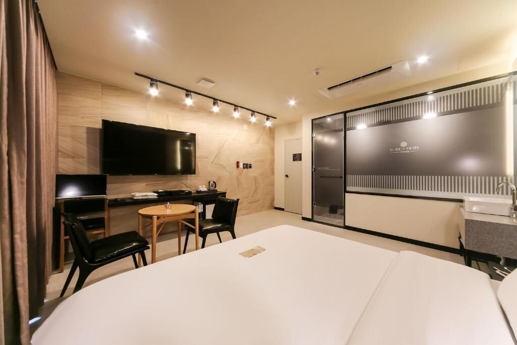 A hotel room with a bed, a desk with a chair, a television, and a sliding door with a mirror.