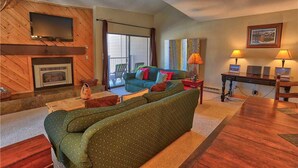 Una sala de estar acogedora con chimenea, televisor, sofá y mesa de comedor.