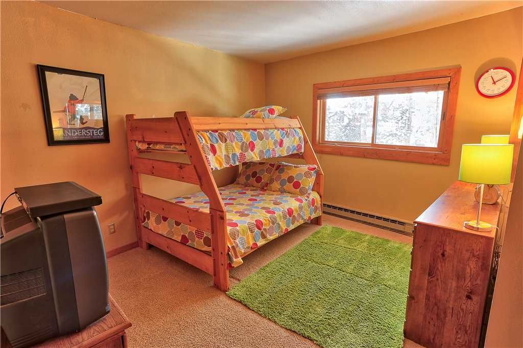 A bunk bed room with a window, a clock, a television, and a lamp.