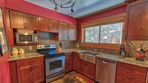 Una cocina con armarios de madera, microondas, estufa, fregadero y lavavajillas.