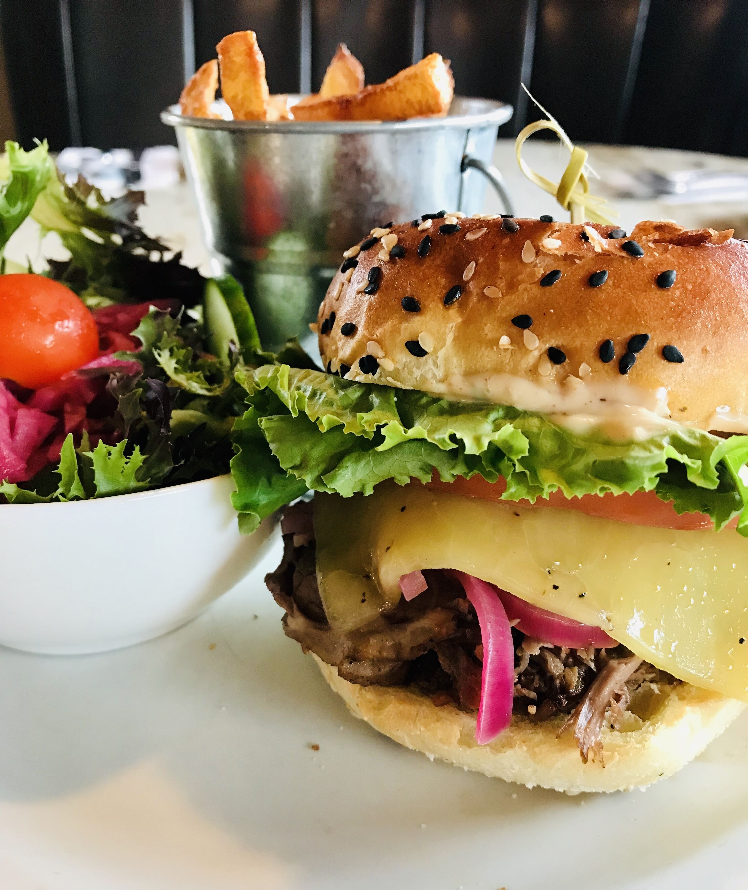 En sandwich med salat, tomat og ost, samt en salat og pommes frites.