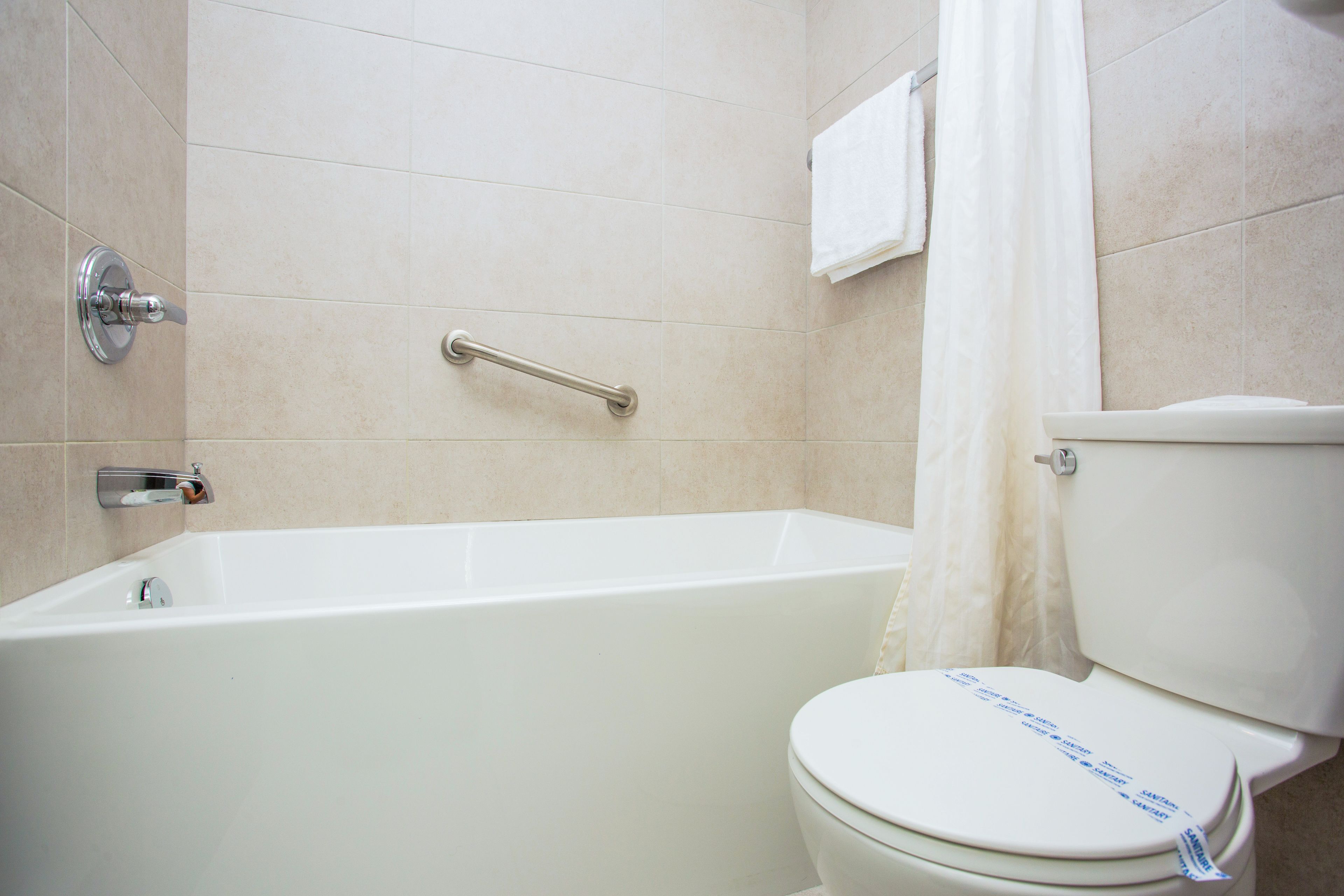 Une salle de bain équipée d’une baignoire, de toilettes et d’une barre d’appui.
