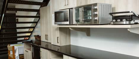 Una cocina con encimera negra, electrodomésticos de acero inoxidable y armarios de madera.