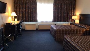 A hotel room with two beds, a desk, a chair, a TV, and a window with curtains.