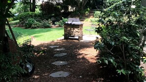 A stone pathway leading through a garden with a stone bench and a small fire feature. - Walk to Death Valley! | Cozy Lakeside Suite (Clemson)