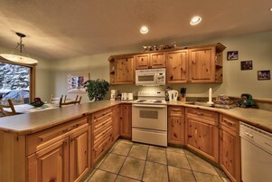 Una cocina con armarios de madera, estufa, microondas y lavavajillas.