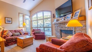 Un salon chaleureux avec une cheminée, un téléviseur et des fauteuils confortables.