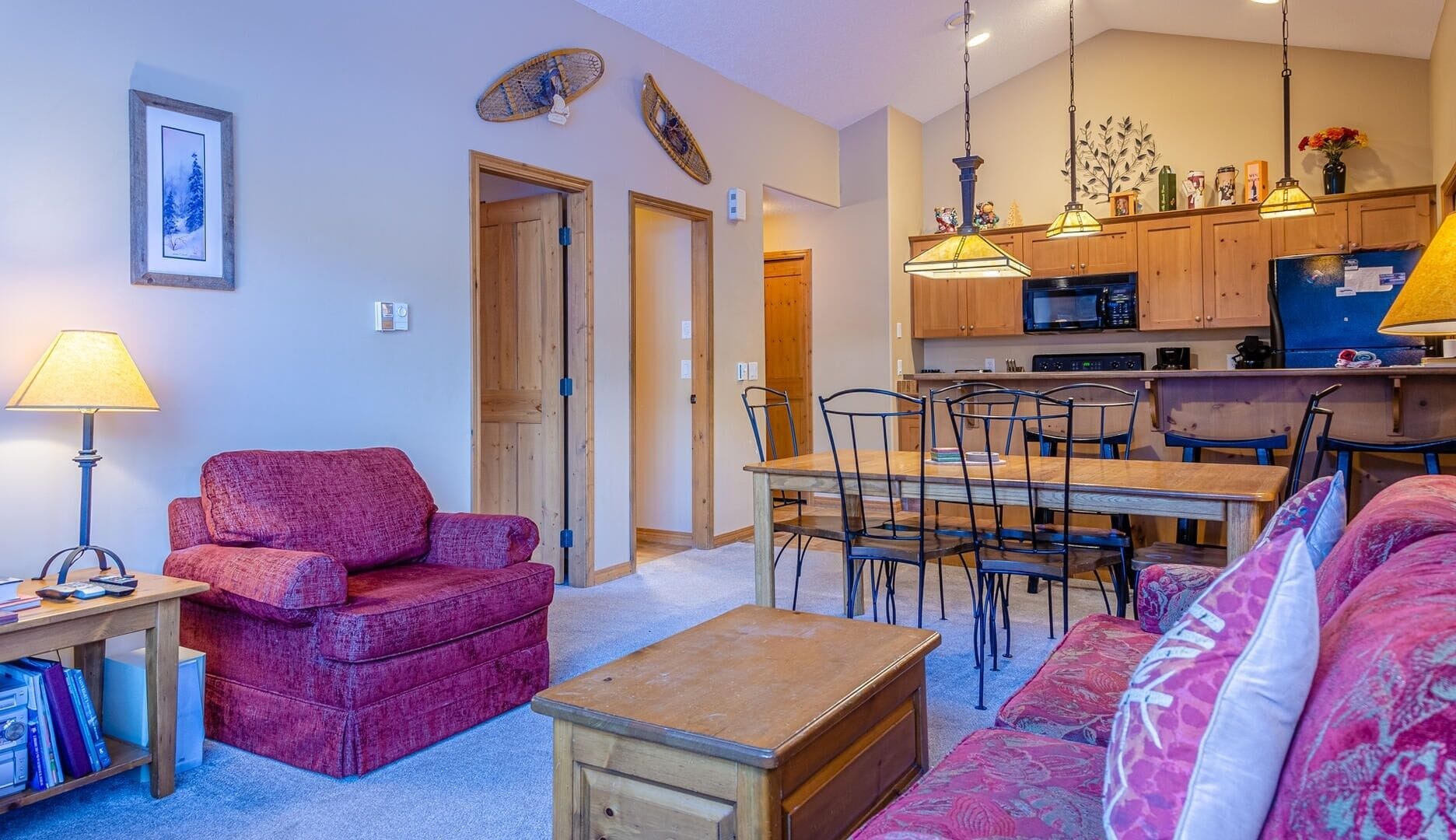 Una sala de estar acogedora con un sofá rojo, una mesa de centro de madera y un comedor con una mesa y sillas de madera.