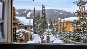 A snowy mountain landscape with a building surrounded by evergreen trees. - Trappers Landing #05 By Bear Country (Sun Peaks)
