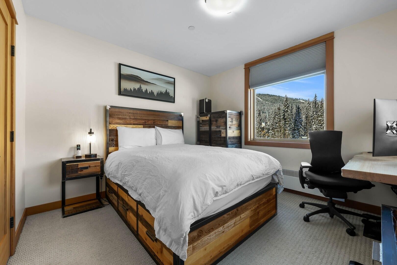 A bedroom with a bed, bedside tables, a desk, and a chair.