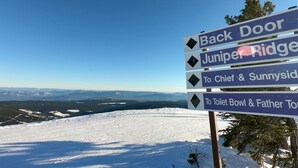 Un panneau indicateur indiquant les directions vers différents lieux, notamment Back Door, Juniper Ridge, Chief & Sunnyside, et Toilet Bowl & Father Town.