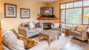 A cozy living room with a fireplace, two sofas, a coffee table, and a TV. - Woodhaven #32 By Bear Country (Sun Peaks)