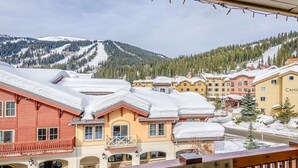 A snow-covered mountain town with buildings and a ski slope in the background. - Fireside Lodge #413 By Bear Country (Sun Peaks)