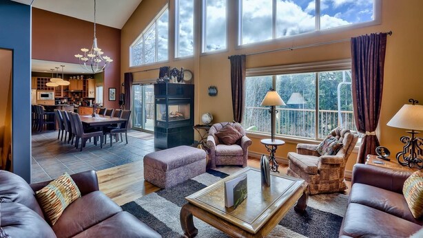 A spacious living room with a fireplace, large windows, and a dining area.