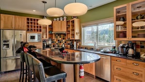 A modern kitchen with wooden cabinets, a central island, and pendant lighting.