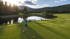 A golf course with a pond, trees, and a mountain in the background.