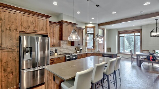 A modern kitchen with wooden cabinets, stainless steel appliances, and a large island with bar stools.