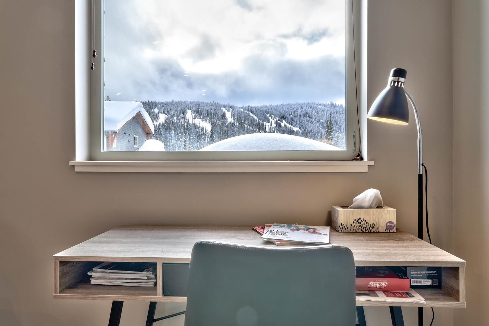 Une pièce comprenant un bureau, une chaise, une lampe, une boîte de mouchoirs et un magazine.