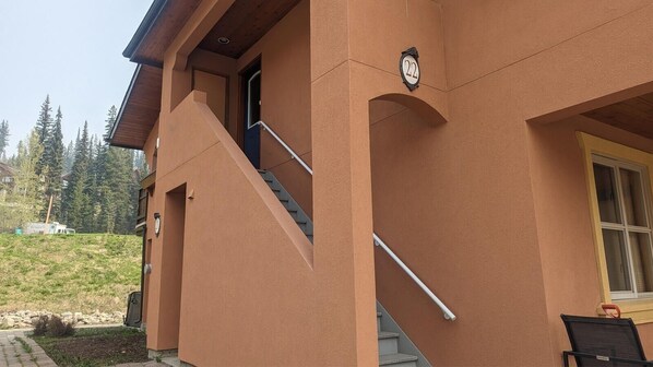 A building with a brown exterior, a visible staircase, and a mailbox. - Crystal Forest #22 By Bear Country (Sun Peaks)