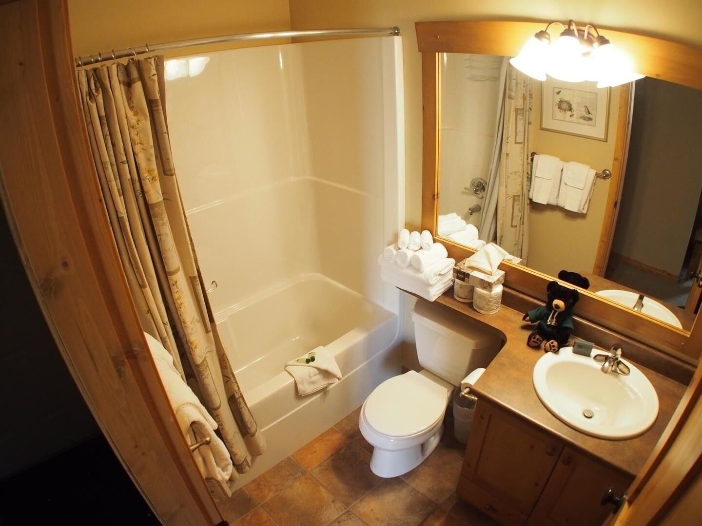 Une salle de bain équipée d’une baignoire, de toilettes, d’un lavabo et d’un miroir avec un porte-serviettes.