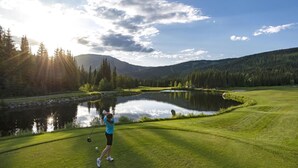 A golf course with a pond, trees, and a mountain in the background. - Trappers Landing #11 (Sun Peaks)