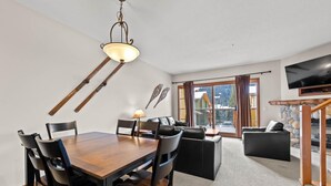 Ein modernes Wohnzimmer mit Essbereich, Kamin und großem Fenster mit Blick auf ein Gebirge.
