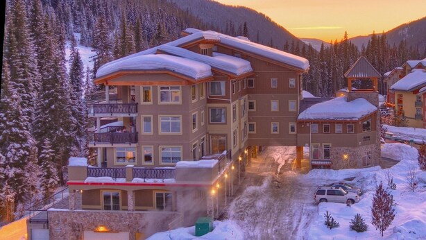 A multi-story hotel with balconies, a ski lift, and a snow-covered landscape.