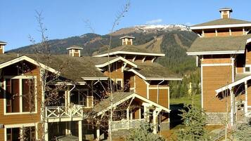 A cluster of wooden cabins with a mountain backdrop.