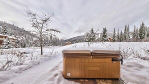 A wooden hot tub in a snowy outdoor setting with a clear sky.