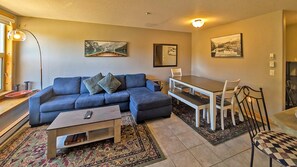 A living room with a sofa, coffee table, dining table, chairs, and a rug.