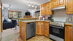 Una cocina compacta con armarios de madera, lavavajillas, estufa y cafetera.