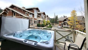 A hot tub on a balcony with views of residential buildings and a clear sky.