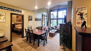 A hotel room with a dining area, a bed, a Christmas tree, and a ski-themed poster. - Stones Throw #38 By Bear Country (Sun Peaks)