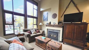 A living room with a fireplace, a television, and a large window.