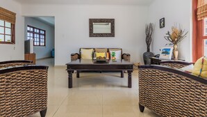 A living room with a sofa, two wicker chairs, a coffee table, and a mirror on the wall. - Grand home with a private pool, close to beach (Noord)