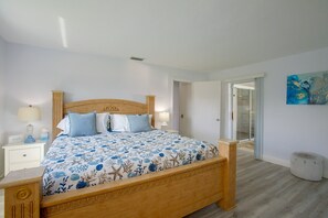 Een slaapkamer met een houten bed, witte nachtkastjes en een blauw beddegoed met bloemen.