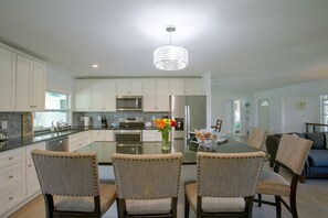 A modern kitchen with white cabinetry, stainless steel appliances, and a central island with chairs. - Cape Coral Home w/ Spacious Patio & Private Pool! (Cape Coral)