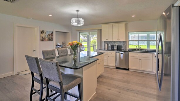 A modern kitchen with a central island, stainless steel appliances, and a view to the outdoors.