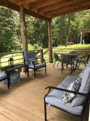 Un espace extérieur abrité, doté d’un sol en bois, de chaises à structure métallique et d’une table.
