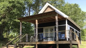 Eine rustikale Holzhütte mit einer Holzterrasse, einer Treppe und einem Hund auf der Veranda.