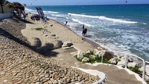 A beach with a rocky shoreline, a paved walkway, and a railing overlooking the ocean. - Beach front condo! Best spot to kite!! Beach lovers paradise! Nanny Estates.! (Cabarete)