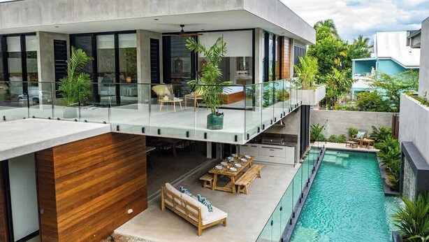 A modern house with a glass balcony, a swimming pool, and outdoor seating. - Azure Port Douglas - Luxurious & Modern Villa (Port Douglas)