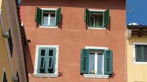A multi-story building with balconies, a central air conditioning unit, and a small awning over the entrance. - Apartment Al Porto (Rovinj)