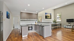 Een moderne keuken met een centraal eiland, een inbouwoven en een vaatwasser.