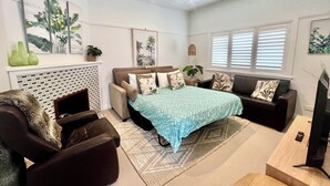 A modern living room with a sofa set, a bed with a patterned bedspread, and artwork on the walls. - Manly Beach Retreat in walkable great location, with bonus rare onsite parking (Manly)