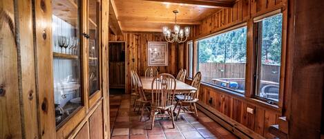 L’intérieur d’un chalet en bois comprend un coin repas, de grandes fenêtres et un sol carrelé.