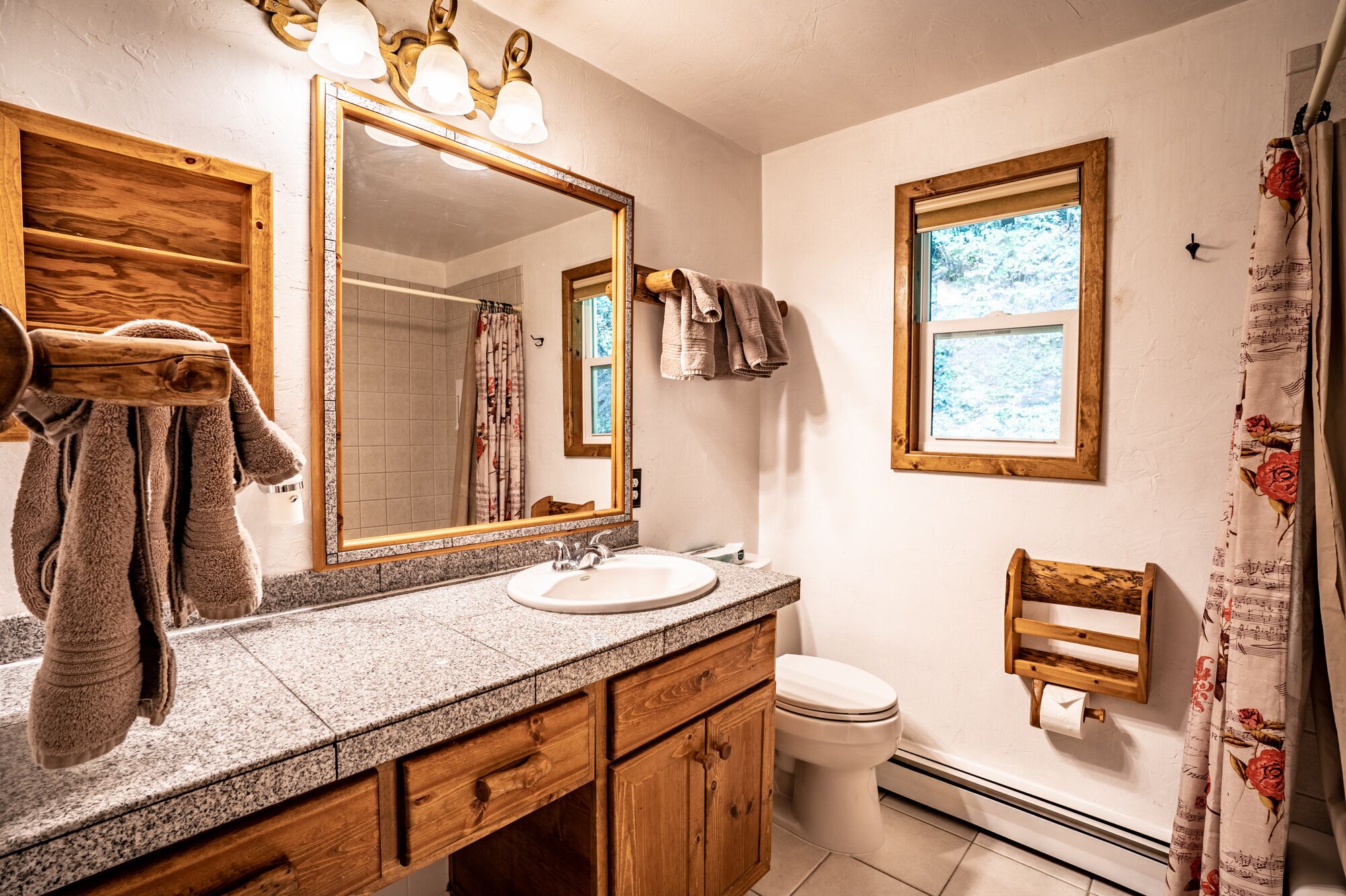 A bathroom with a wooden vanity, a large mirror, a sink, and a toilet.