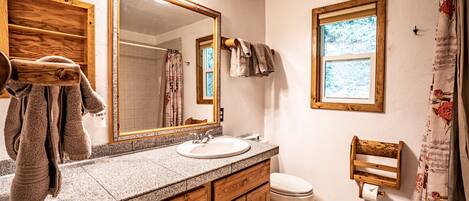 A bathroom with a wooden vanity, a large mirror, a sink, and a toilet.