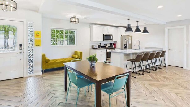 A modern kitchen with white cabinets, a central island, and bar stools.