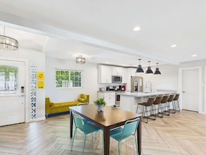 A modern kitchen with white cabinets, a central island, and bar stools.